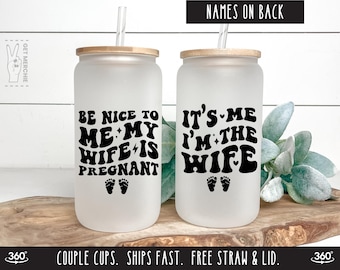 May include: Two frosted glass tumblers with black text and a pair of footprints. The tumbler on the left says "Be nice to me my wife is pregnant". The tumbler on the right says "It's me I'm the wife".