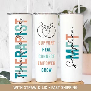 May include: Three white tumblers with colorful text and designs. The tumbler on the left says "Marriage & Family Therapist". The tumbler in the middle says "Support, Heal, Connect, Empower, Grow". The tumbler on the right says "Seraphina Meet".