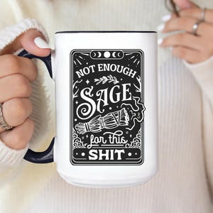 以下が含まれることがあります： 黒い内側とハンドルが付いた白いセラミックマグ。マグには、「NOT ENOUGH SAGE for this SHIT」というテキストとセージの束が描かれた白黒のグラフィックが施されています。