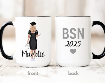 May include: White ceramic mug with a black handle and rim. The front features an illustration of a graduate in a black dress and cap, with the name "Maddie" below. The back of the mug displays "BSN 2025" with a gray heart.