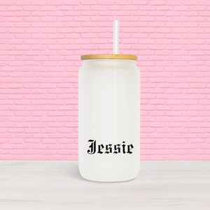 Puede incluir: Un vaso de vidrio esmerilado blanco con tapa de bamb&uacute; y una pajita negra. El vaso tiene el nombre "Jessie" impreso en la parte delantera en una fuente g&oacute;tica negra.