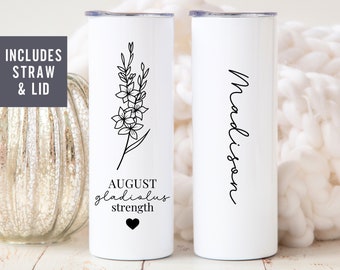 May include: Two white stainless steel tumblers with lids. One tumbler features a black line drawing of a flower with the text "AUGUST gladiolus strength" and a black heart. The other tumbler has the name "Madison" written in black cursive.