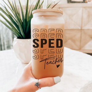May include: A clear glass jar with a bamboo lid and a black and white graphic that reads "SPED Teacher" with a small heart. The jar is filled with a light brown liquid.