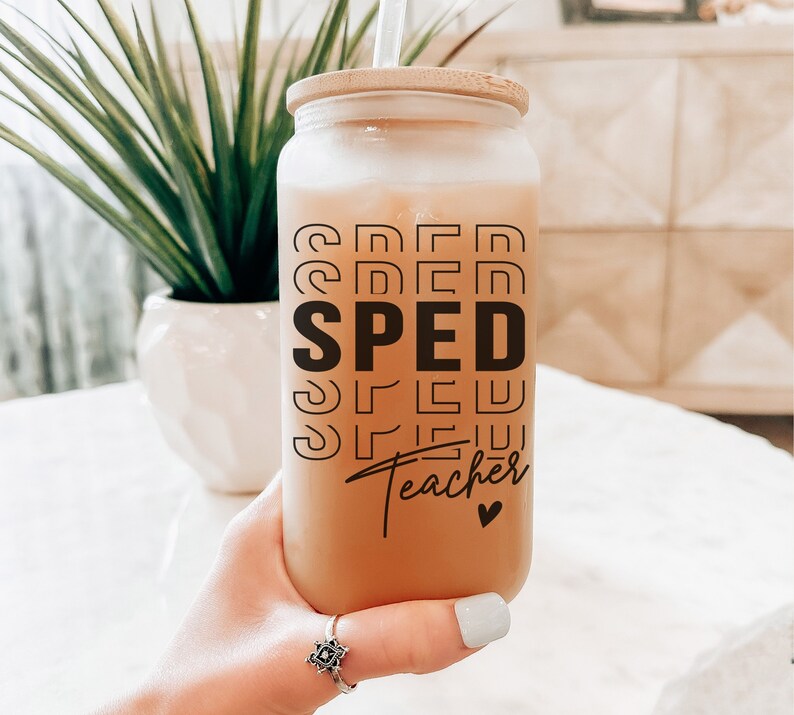 May include: A clear glass jar with a bamboo lid and a black and white graphic that reads "SPED Teacher" with a small heart. The jar is filled with a light brown liquid.