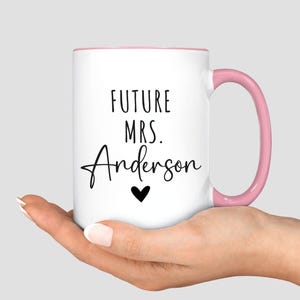 May include: White ceramic mug with a pink interior and handle. The mug features the text "FUTURE MRS. Anderson" in black script, with a small black heart below the name. A perfect gift for a future bride.
