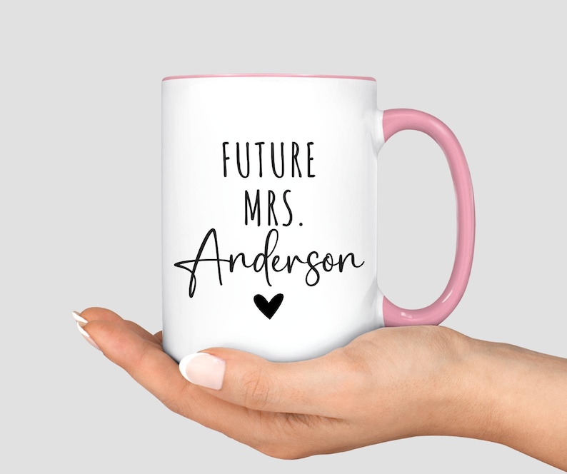 May include: White ceramic mug with a pink interior and handle. The mug features the text "FUTURE MRS. Anderson" in black script, with a small black heart below the name. A perfect gift for a future bride.