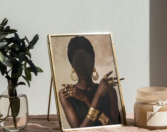 May include: A framed art print featuring a woman wearing a black head wrap, gold jewelry, and a black top. The gold frame stands on a pink surface, with a vase of greenery and a candle jar nearby.