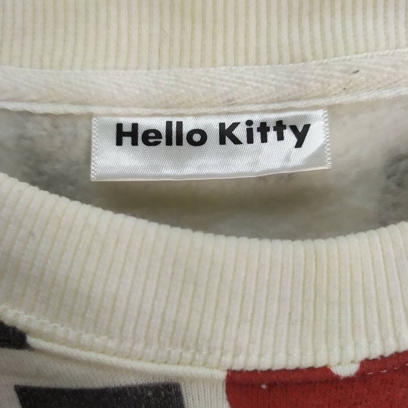 May include: White sweatshirt with a Hello Kitty label. The sweatshirt has a colourful graphic print.
