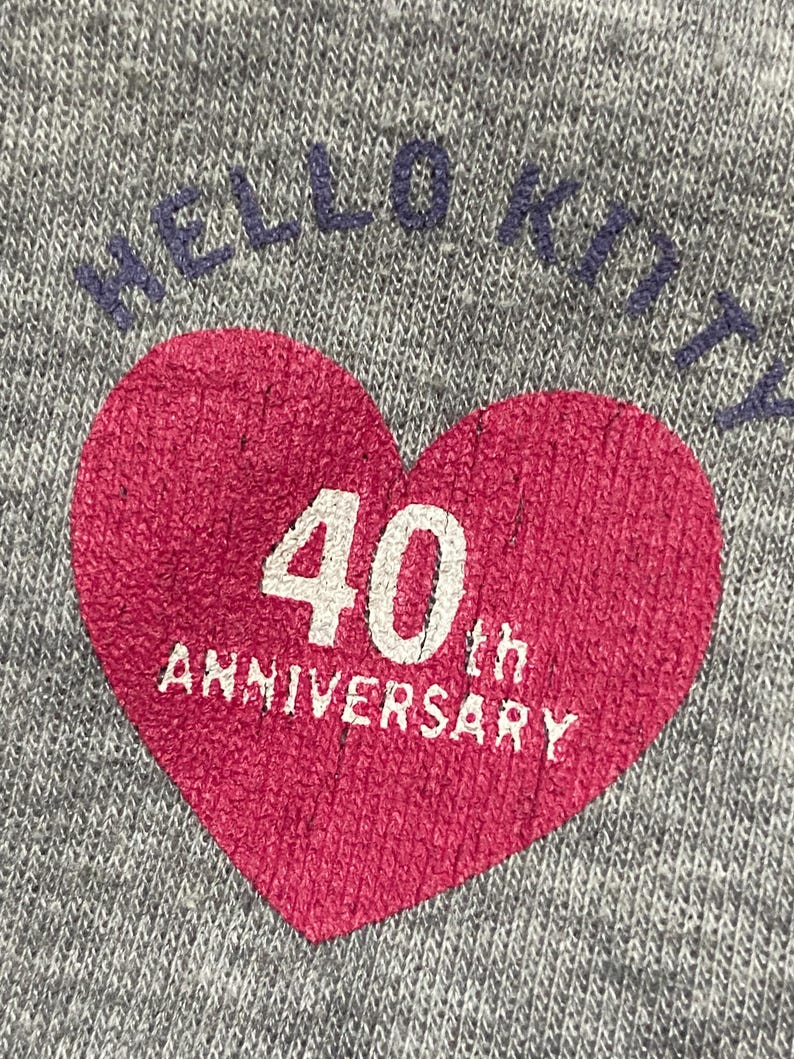 May include: Grey sweatshirt with a red heart graphic that says "40th Anniversary" and "Hello Kitty" in blue lettering.