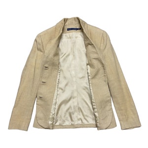 May include: A beige blazer with a  "RALPH LAUREN" label on the inside collar. The blazer has a  double-breasted closure and a  satin lining.