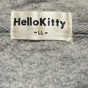 May include: A white tag with black text that reads "Hello Kitty" and "LL" on a grey sweatshirt.