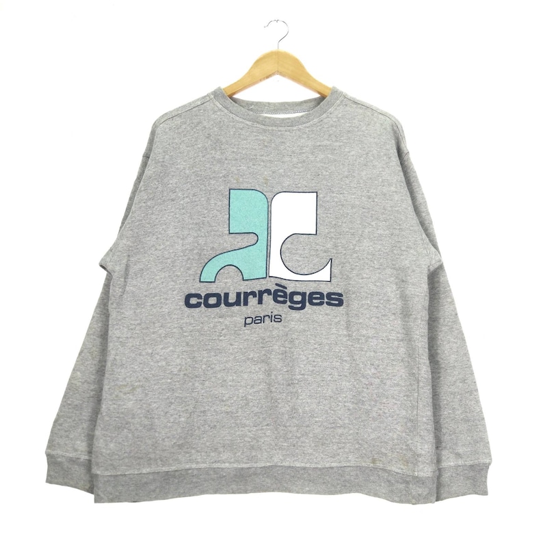 May include: Gray sweatshirt with a blue and white logo that says "Courr&egrave;ges Paris".