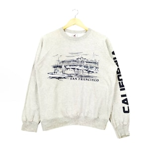 May include: A gray sweatshirt with a graphic print of a building and boats with the text "SAN FRANCISCO" and "CALIFORNIA" on the sleeve.