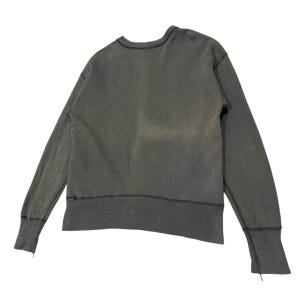 May include: A dark gray sweatshirt with long sleeves. The crew neck and cuffs have a raw edge design. The garment has a faded appearance, suggesting a vintage or worn aesthetic. The stitching is visible along the seams.