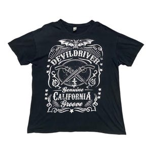 Puede incluir: Camiseta negra con un diseño gráfico blanco con el nombre de la banda "DevilDriver" y el texto "Genuine California Groove".