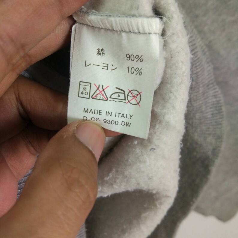 May include: White clothing label with black text that reads "綿 90% レーヨン 10%" and "MADE IN ITALY D-OS-9300 DW". The label also has a washing instruction symbol.