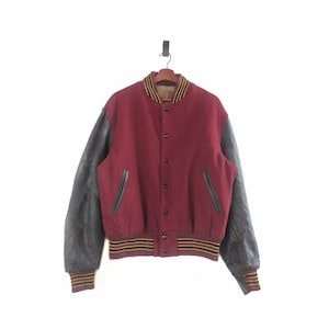 May include: A maroon varsity jacket with black leather sleeves and yellow and black striped ribbing around the collar, cuffs, and waist.