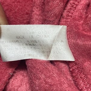 K&ouml;nnte beinhalten: Nahaufnahme eines rosa Stoff-Etiketts mit wei&szlig;em Text, der "MADE IN CHINA" lautet, und anderem Text in einer Fremdsprache.