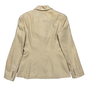 May include: A beige blazer with a single-breasted closure and long sleeves. The blazer has a textured fabric and a classic design.
