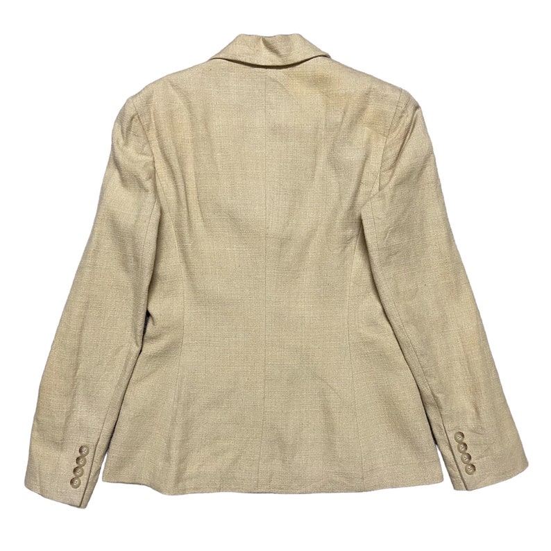 May include: A beige blazer with a single-breasted closure and long sleeves. The blazer has a textured fabric and a classic design.