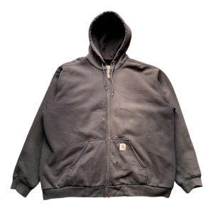 Pode incluir: Um moletom com capuz cinza escuro com z&iacute;per, bolso frontal e capuz. O moletom tem um pequeno patch com o logotipo na frente e um fecho de z&iacute;per. Existem pequenas marcas de tinta no tecido.