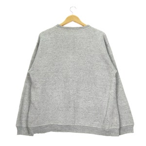 May include: A gray sweatshirt with long sleeves and a crew neck.