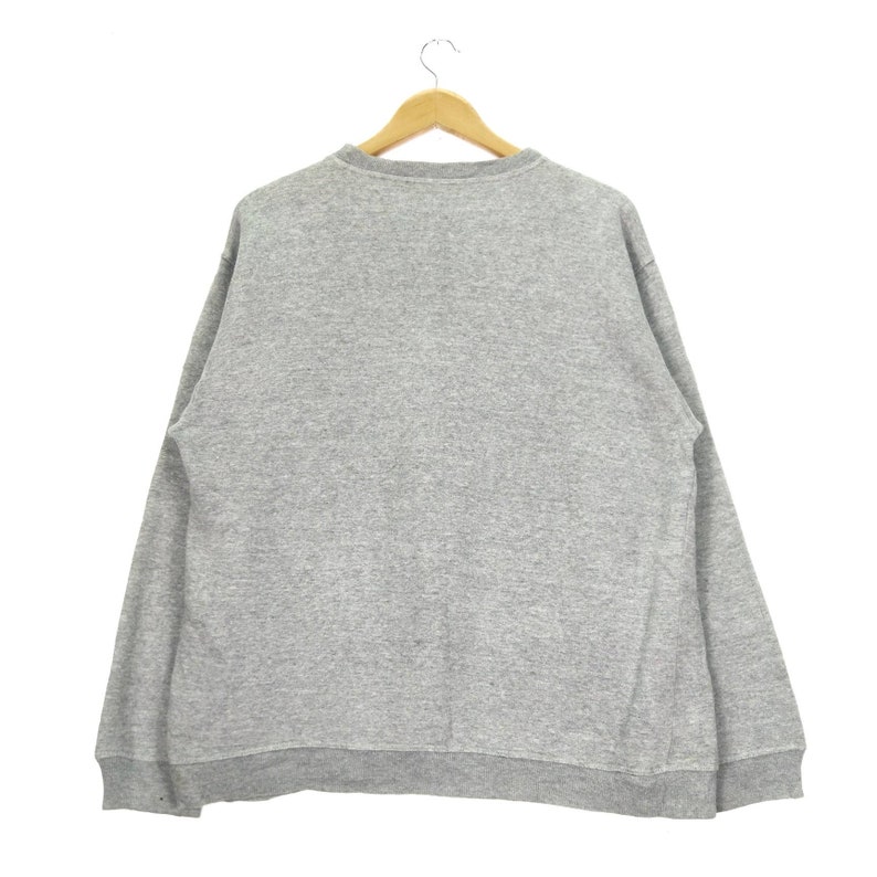 May include: A gray sweatshirt with long sleeves and a crew neck.