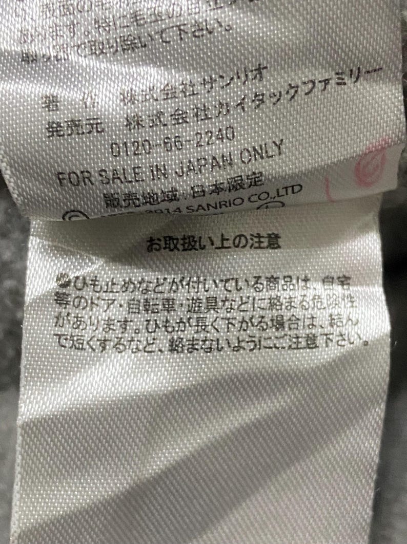 May include: A white tag with black text that reads "For Sale in Japan Only" and "2014 Sanrio Co., Ltd."  The tag also includes a warning about loose strings and how to prevent them from becoming entangled.