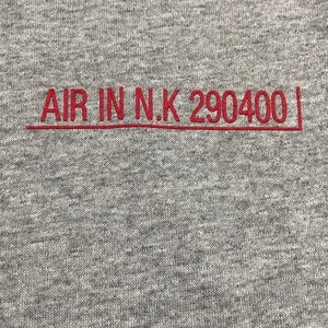 May include: Gray sweatshirt with red embroidered text that reads "AIR IN N.K 290400".