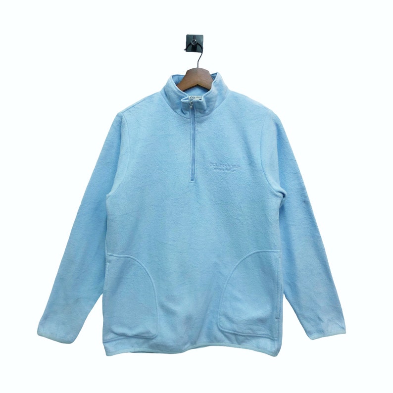 May include: A light blue fleece pullover with a half-zip closure and a small embroidered logo that reads "SUPERIOR FLEECE" on the front.