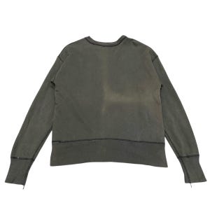 May include: A faded olive green long-sleeve sweatshirt. The crew neck sweatshirt has a relaxed fit with ribbed cuffs and a stitched hemline. The fabric appears to be a soft, worn material.
