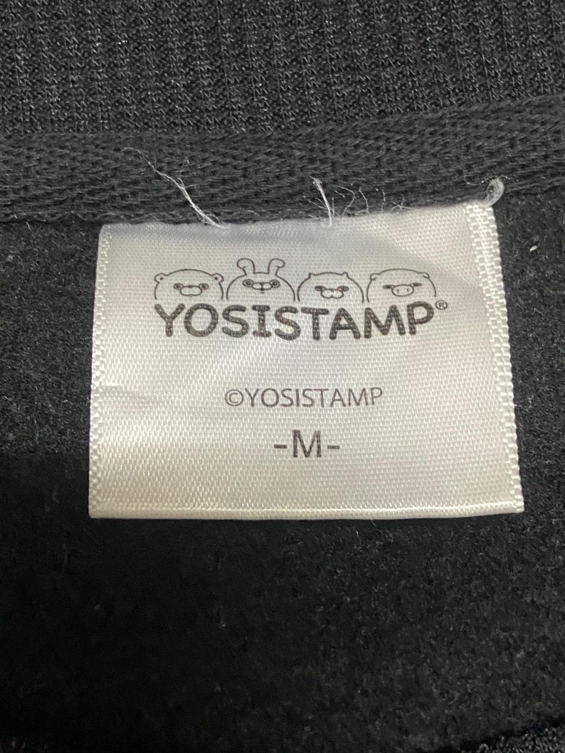 May include: White tag with black text that reads "YOSISTAMP" with three cartoon animal faces above the text. Below the text is "OYOSISTAMP" and "M".