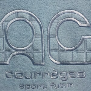 May include: A light blue fleece jacket with a white embroidered logo that says "Courr&egrave;ges sport futur".