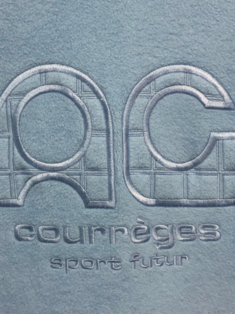 May include: A light blue fleece jacket with a white embroidered logo that says "Courr&egrave;ges sport futur".