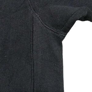 May include: Close-up of the black ribbed fabric of a sweatshirt sleeve.