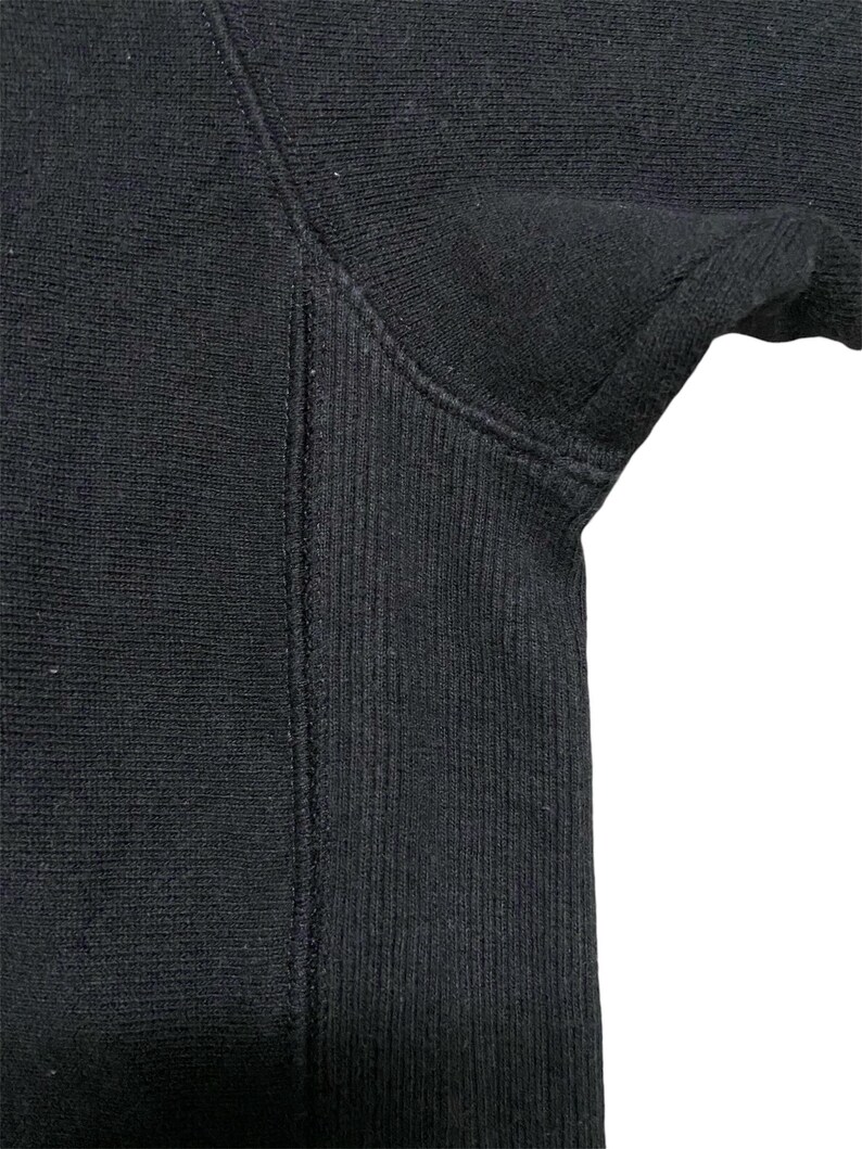 May include: Close-up of the black ribbed fabric of a sweatshirt sleeve.