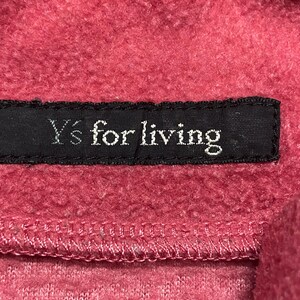 K&ouml;nnte beinhalten: Nahaufnahme eines roten Fleece-Stoffes mit einem schwarzen Etikett, auf dem "Y's for living" steht.