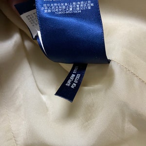 May include: A blue fabric label with white text and symbols. The text includes "17% Wool, 6% Linen, 100% Cotton", "Dry Clean Only", "Supplier# 11101", and "PO# 977333".