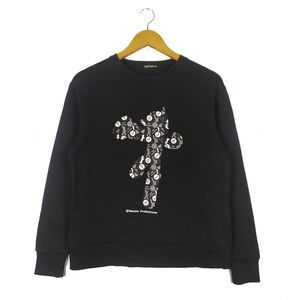 May include: Black long-sleeved sweatshirt featuring a graphic print of a stylised figure composed of smaller figures. The text "©Tsuchida Productions" is printed below the graphic.