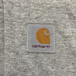 May include: A gray Carhartt workwear patch with a brown logo and the word "carhartt" in white lettering.