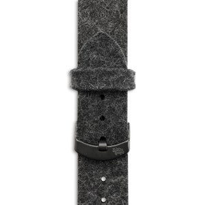 Può includere: Un cinturino da orologio nero in feltro grigio con una fibbia in metallo nero. La fibbia ha inciso il testo "Sindre Cops".