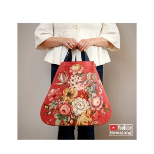 Op de afbeelding: Een grote rode tote bag met een bloemenprint. De tas heeft zwarte handvatten en een YouTube Sewalong-logo.