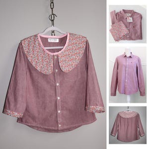 May include: A mauve button-down shirt with a floral print collar and cuffs. The collar and cuffs feature a pattern of small red, pink, and white flowers on a cream background. The shirt has a chest pocket and is hanging on a gray hanger.