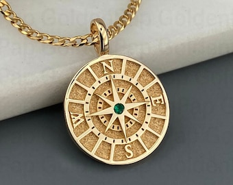 May include: Gold compass necklace with a green gemstone in the center. The compass features the cardinal directions N, E, S, and W.