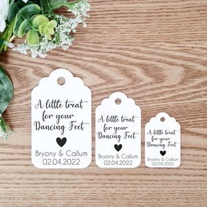 May include: Three white favour tags with scalloped edges and a black heart. The tags read "A little treat for your Dancing Feet" with the names "Bryony & Callum" and the date "02.04.2022".