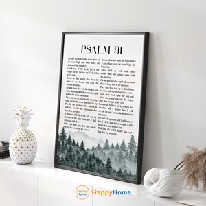 May include: A framed print featuring Psalm 91 text with a forest scene at the bottom. The black frame surrounds the white text and a grayscale image of trees. The print is displayed on a white surface.