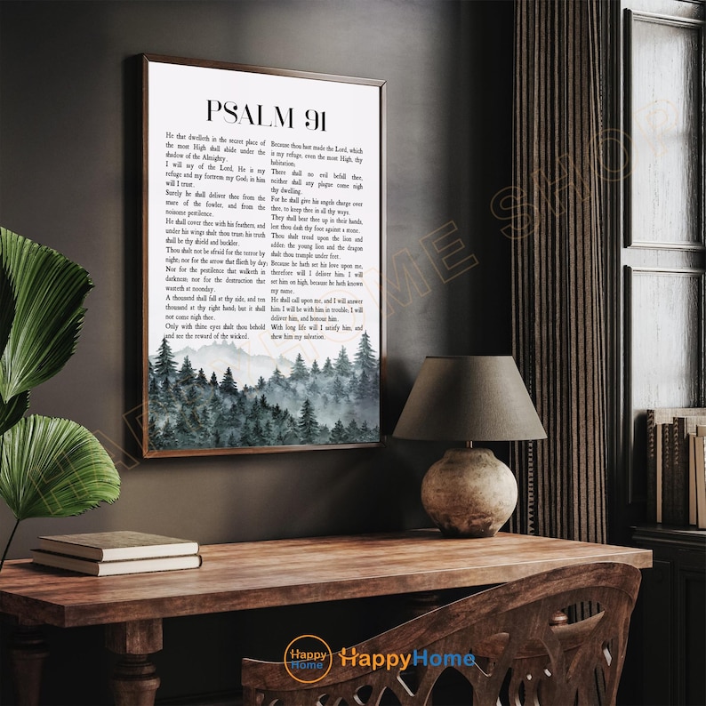 May include: A framed print of Psalm 91, featuring a forest landscape at the bottom. The text is in black on a white background. The frame is brown, and the print is displayed on a wooden desk with a lamp.