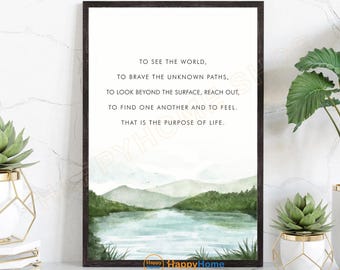 May include: A framed art print with a watercolor landscape scene. The artwork features a lake, mountains, and trees in shades of green and blue. Text at the top reads: "TO SEE THE WORLD... THAT IS THE PURPOSE OF LIFE."
