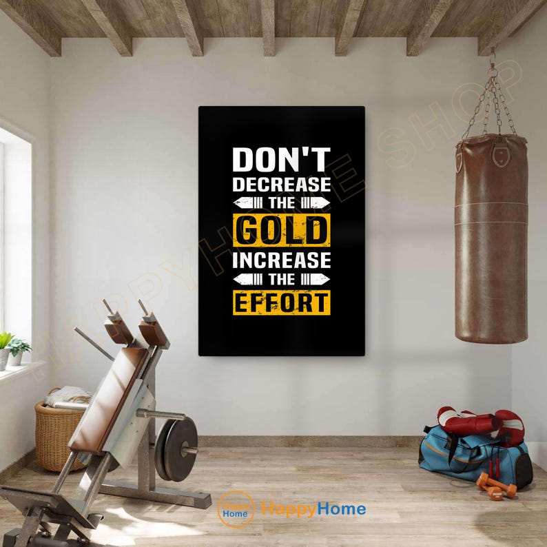 May include: Black rectangular wall art with the text "DON'T DECREASE THE GOLD INCREASE THE EFFORT" in white and yellow. The image is in a gym setting with exercise equipment and a punching bag.