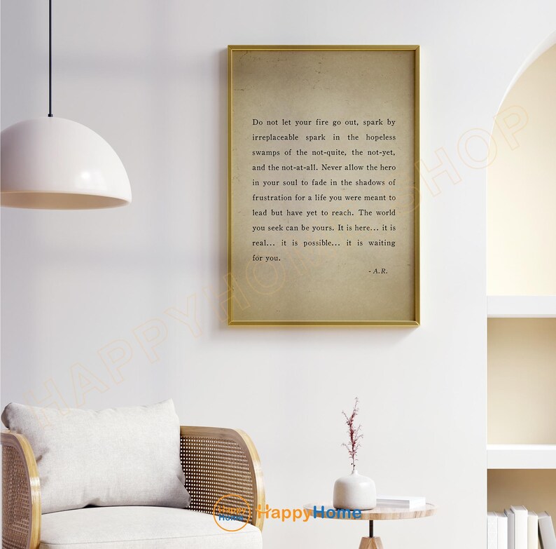 Op de afbeelding: Een ingelijste print met een gouden rand met inspirerende tekst op een beige achtergrond. De tekst bevat de zin "Laat je vuur niet doven..." en is gesigneerd met "-A.R." De print wordt op een witte muur weergegeven.